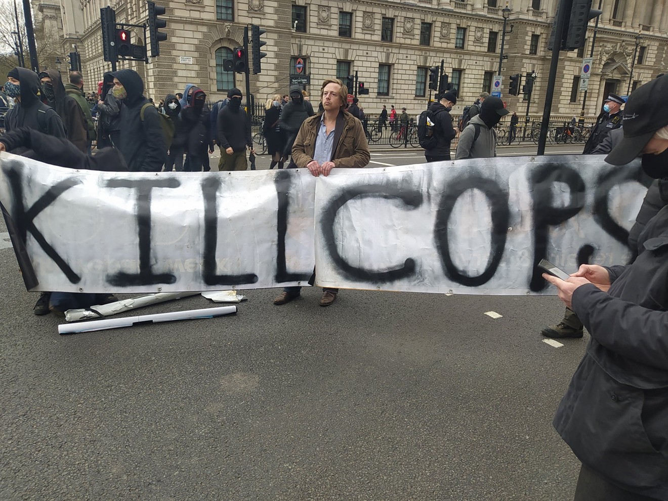 Barrett Brown holds the "Kill Cops" sign at a London protest against a new crime bill.