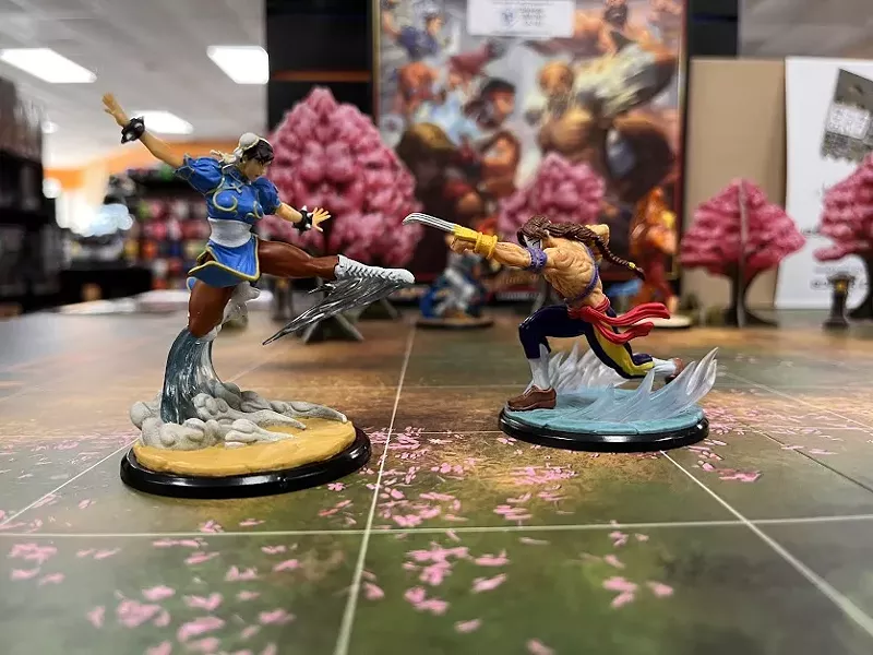Image: Miniature Chun Li, left, and Vega, right, do battle on an end cap demo display table at Common Ground Games, the popular Dallas game store that reopened in a bigger space last month.