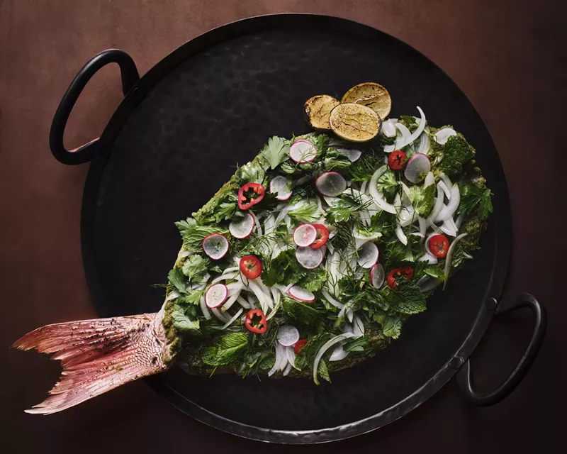 Image: A whole fish is cooked over wood and served topped with mint mojo, fennel and herbs.