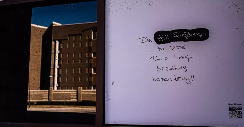 Image: A message scrawled on the back of a sign across the street from the Dallas County Jail echoes the cries of the prisoners.