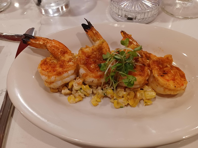Plump and juicy jerk shrimp are served over elote, offering a sweet and spicy kick.