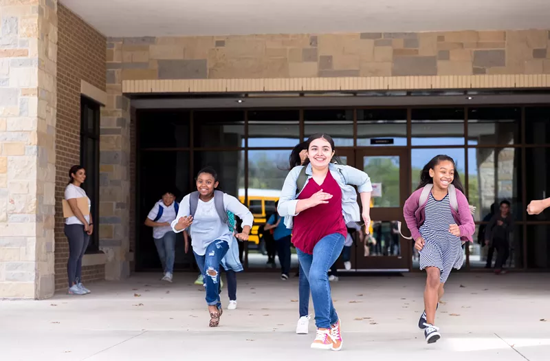 Image: Students running from school with smiles on their faces.