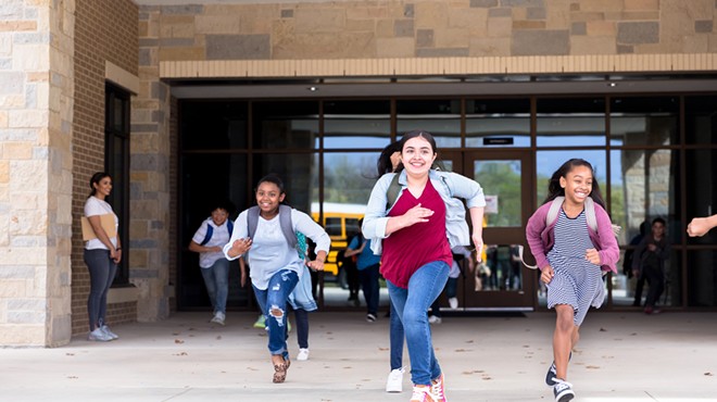 Students running from school with smiles on their faces.