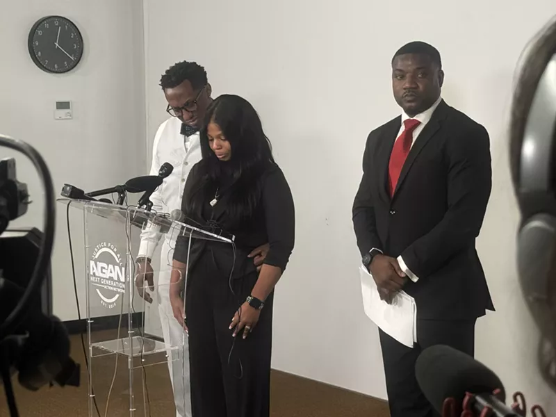 Image: Karmelo Anthony's mother take a breath while delivering remarks during a press conference on April 17, 2025. Dominique Alexander (right) is serving as a family spokesperson.