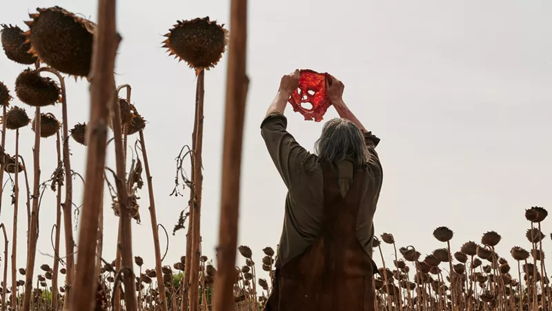Image: The new Leatherface, played by Mark Burnham, holds up a freshly cut face for Netflix's new sequel to the 1973 Texas horror classic The Texas Chain Saw Massacre. 