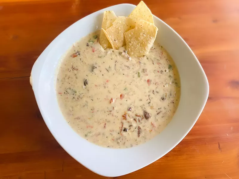 Image: The brisket queso has yellow and orange cheese, smoked brisket and pico de galllo.