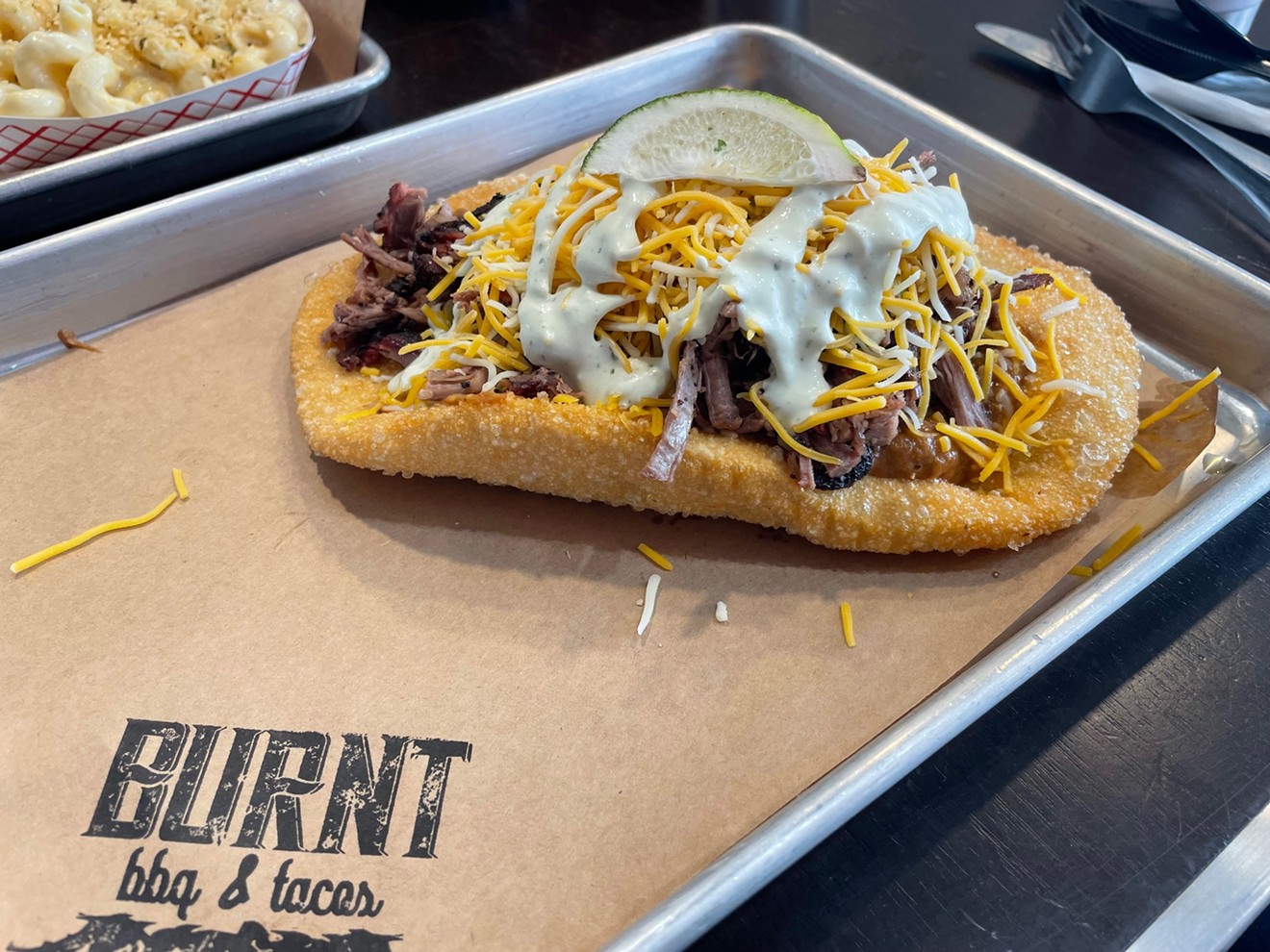 A simple crisp fried bread is topped with beans, brisket and cheese.