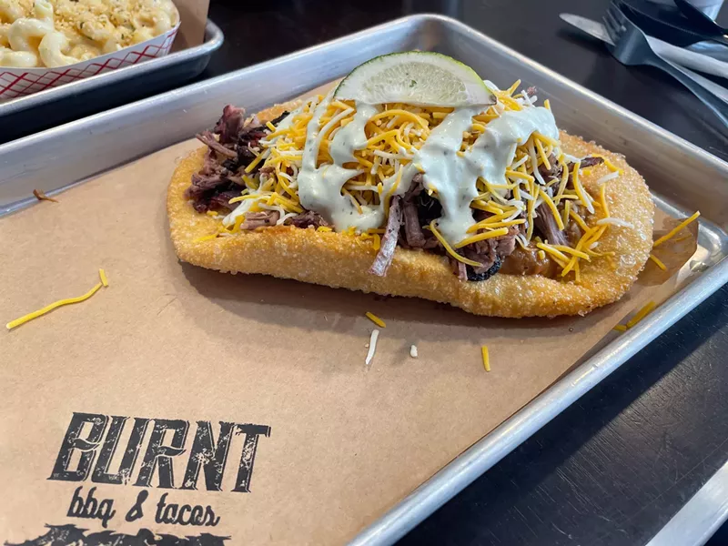 Image: A simple crisp fried bread is topped with beans, brisket and cheese.