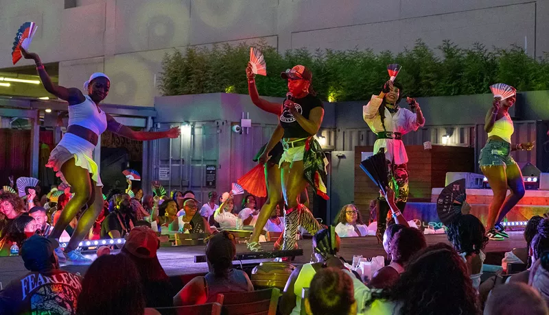 Image: Guests popped their fans and competed in a line dance for a prize at the annual Juneteenth fashion show at the Lexus Box Garden.