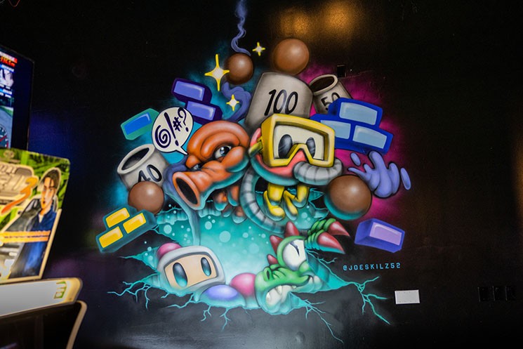 Local artists such as Jose "Skilz" May decorated Free Play Arcade's new Denton location with colorful game murals like this mashup of Dig-Dug and Q*Bert. - COREY HYDEN