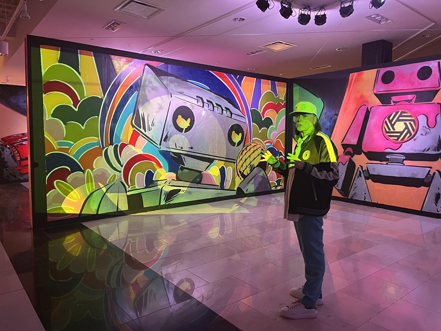 Psychedelic Robot co-founder Michael Bivins takes guests through a preview of the paintings that make up the robot’s origin story. - DANNY GALLAGHER