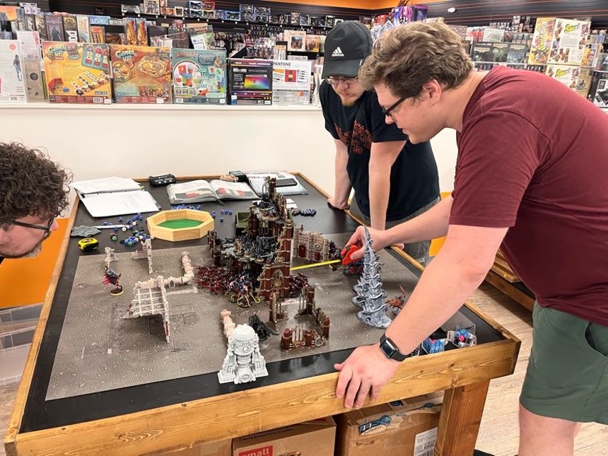 Beavan Blocker uses a tape measure to determine the melee attack range in a game of Warhammer 40,000 at the reopened Common Ground Games on Inwood Road. - DANNY GALLAGHER