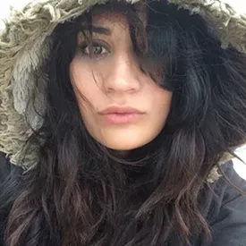 Headshot of a woman with brown hair and a fur hood