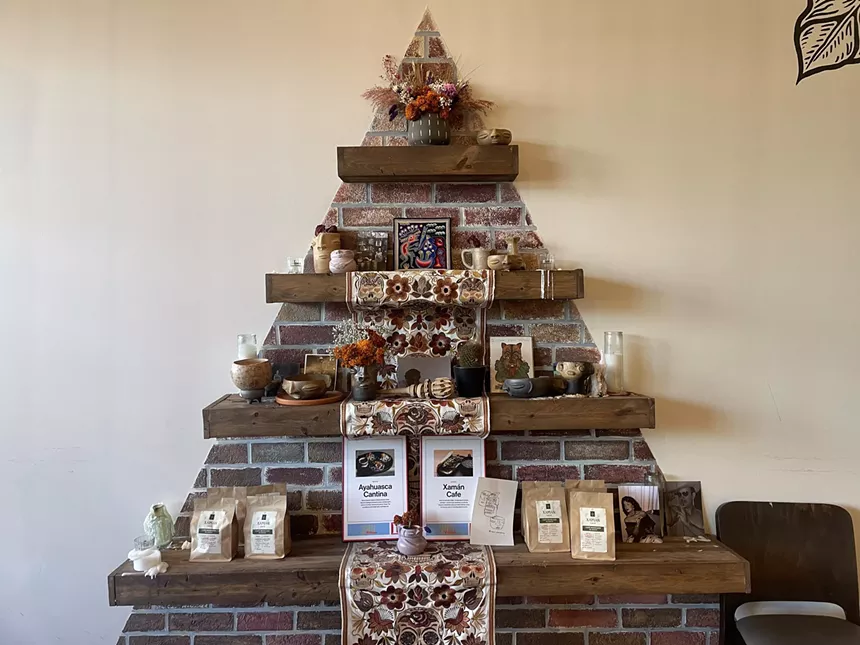 An altar-like wall installation holds a awards, mugs, coffees and art pieces.