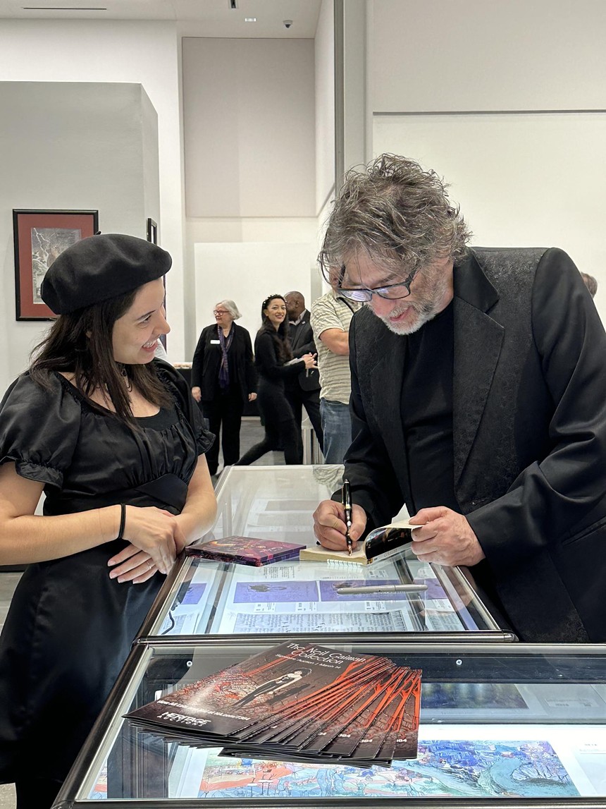A fan gets an autograph from author Neil Gaiman at an auction of his memorabilia.