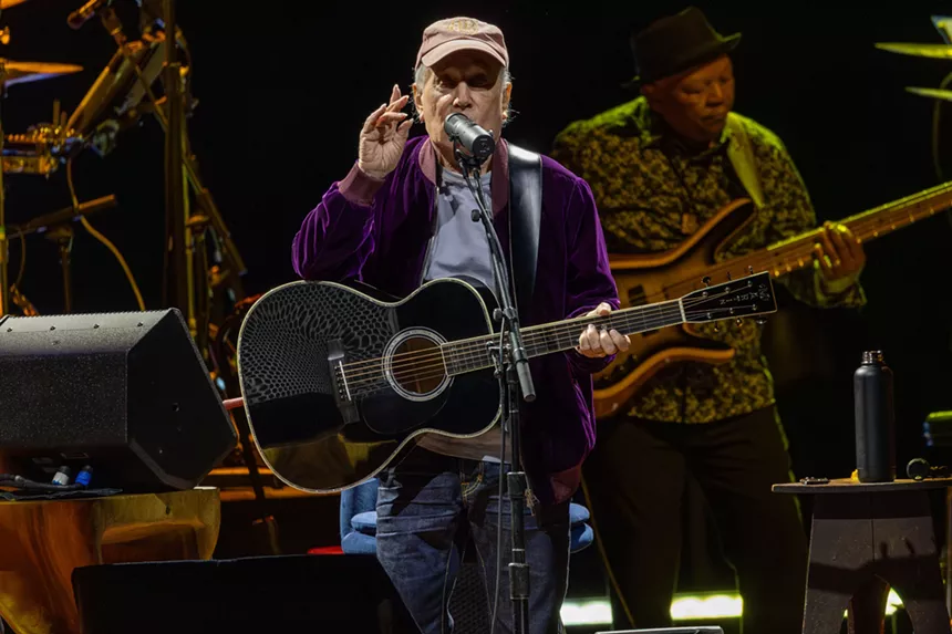 Man performing on stage with a guitar