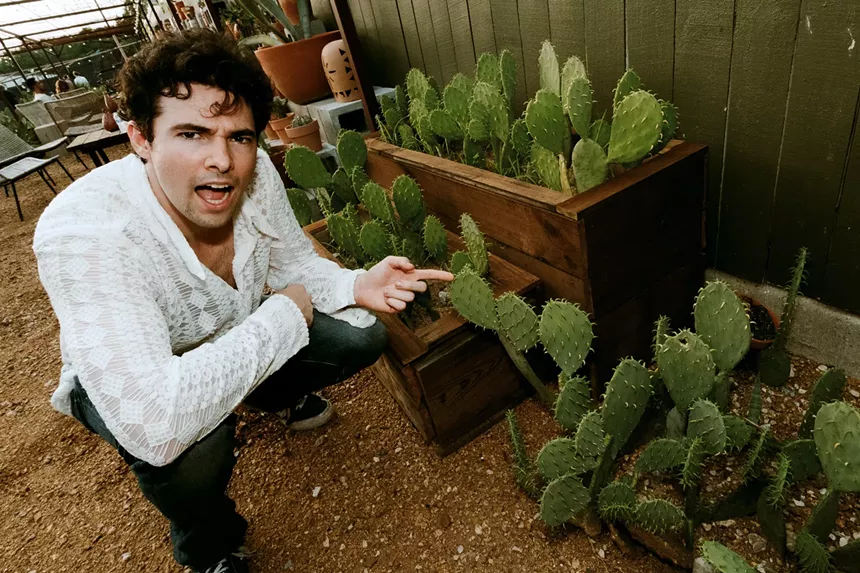 Photo of man in front of cactus.