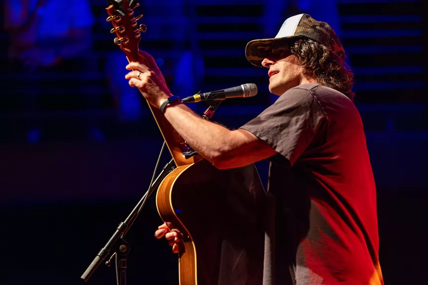 Man performing on stage with a guitar