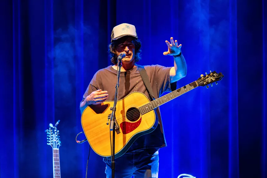 Man performing on stage with a guitar
