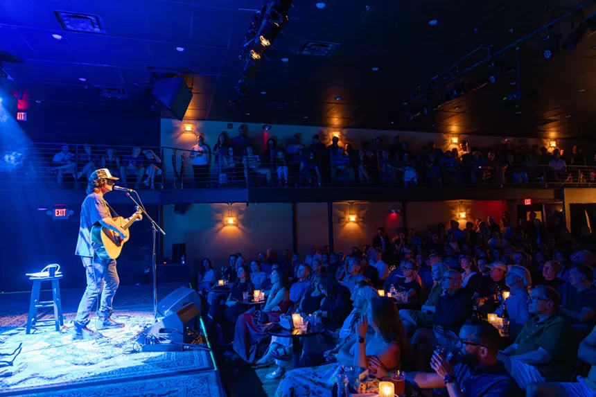 Man performing on stage with a guitar