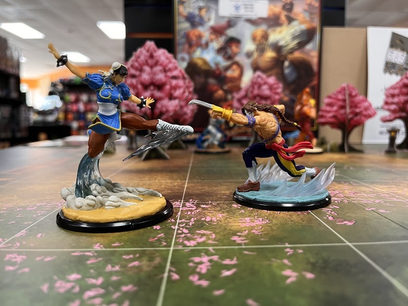 Miniature Chun Li, left, and Vega, right, do battle on an end cap demo display table at Common Ground Games, the popular Dallas game store that reopened in a bigger space last month.